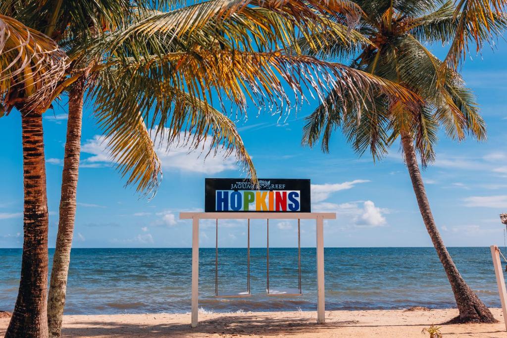 霍普金斯The Lodge at Jaguar Reef的棕榈树海滩上的标志