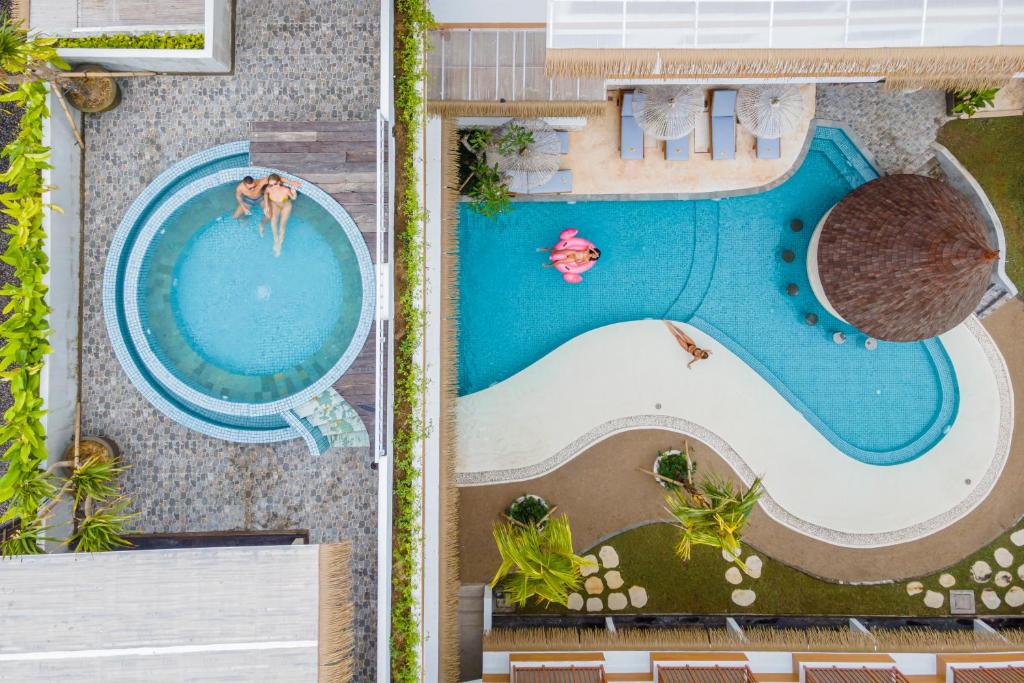 坎古Roomates Hostel Canggu by Ini Vie Hospitality的游泳池的顶部景色,其中有2人
