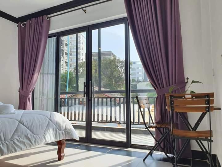 西哈努克Paradise Cozy Guesthouse Sihanoukville的一间卧室配有一张床,阳台配有紫色窗帘