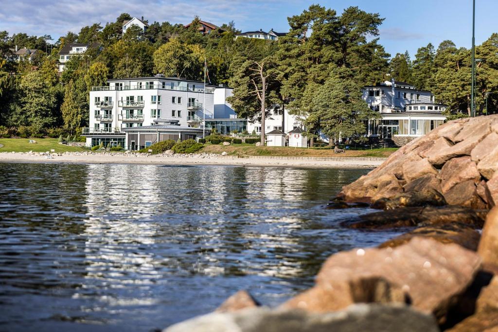 弗维克Strand Hotel Fevik - by Classic Norway Hotels的水体岸边的白色大房子