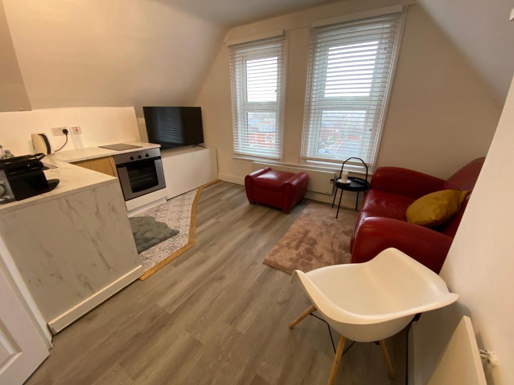 伦敦Cosy flat in London的一间带红色沙发的客厅和一间厨房