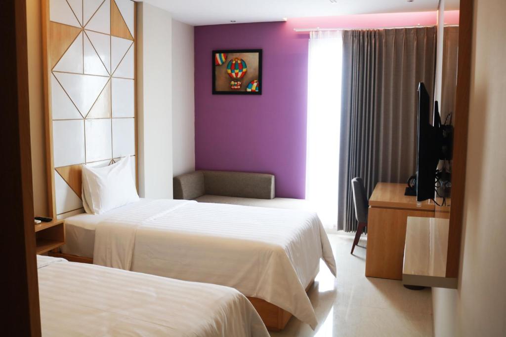 泗水Surabaya River View Hotel的酒店客房设有两张床和紫色墙壁。