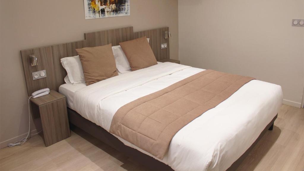 巴黎Hotel Puy De Dôme的一间卧室配有一张大床和木制床头板