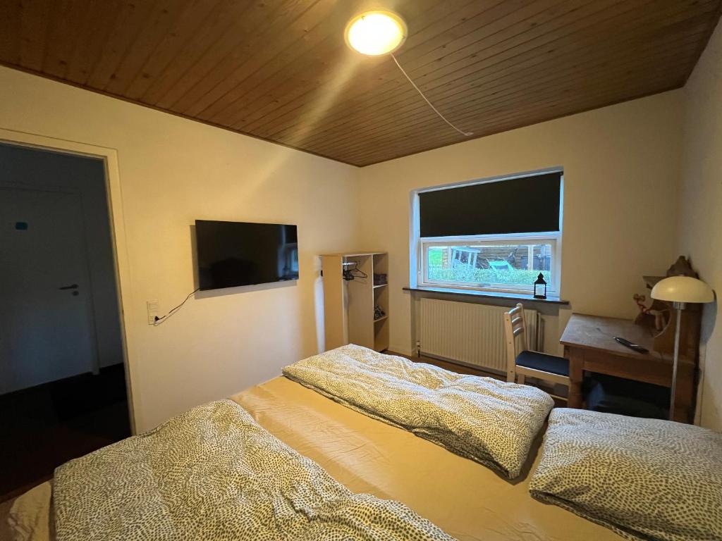 森讷堡Private fully functional apartment in a villa near forrest的一间卧室配有一张床、一张书桌和一个窗户。