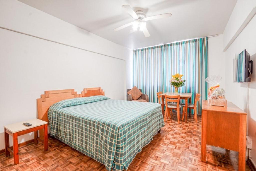 德班Impala Holiday Flats & Apartments的一间卧室配有一张床和一张桌子及椅子