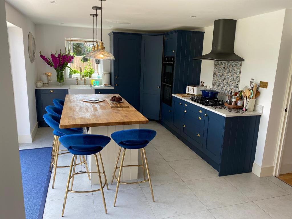 切尔滕纳姆Modern family home central Cheltenham的蓝色的厨房,配有木桌和蓝色凳子