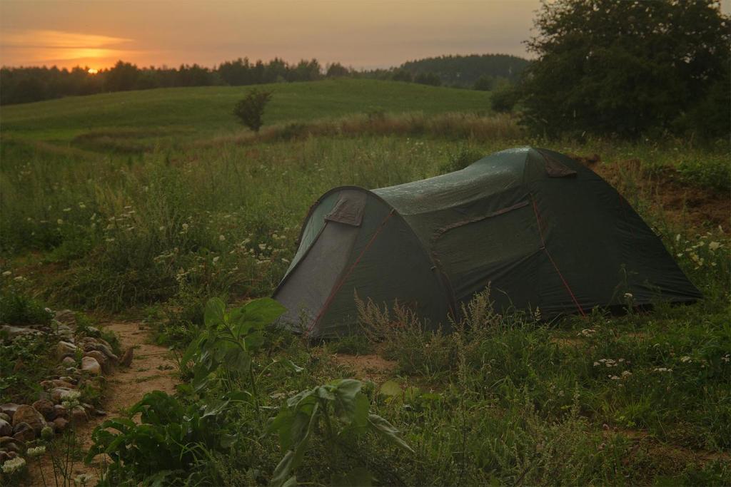 PozezdrzeRent a tent - Namiot w Praekologicznym gospodarstwie的地里的一个帐篷,背景是日落