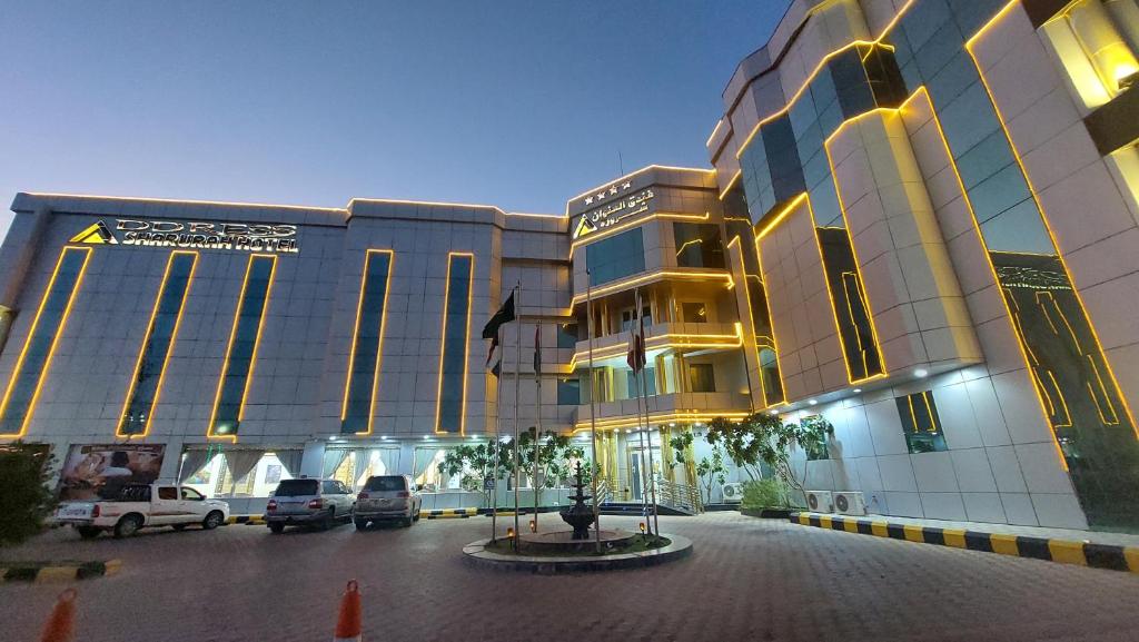 沙鲁拉Address Sharurah Hotel的停车场内停放汽车的大型建筑
