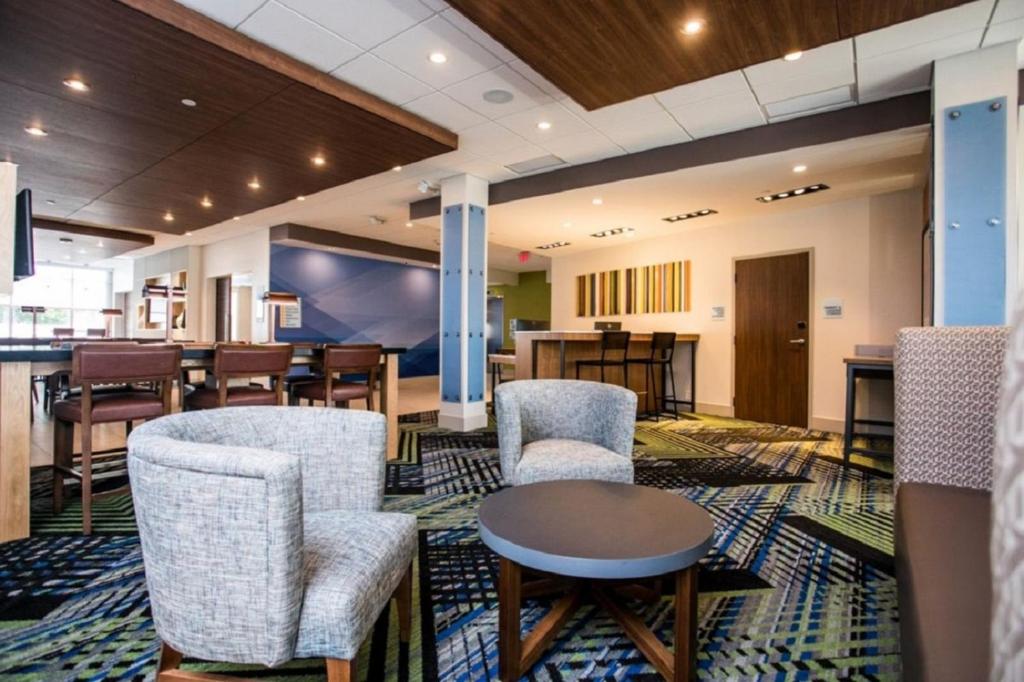 柏斯海滩Holiday Inn Express & Suites Rehoboth Beach, an IHG Hotel的一间设有椅子和桌子的等候室和一间酒吧