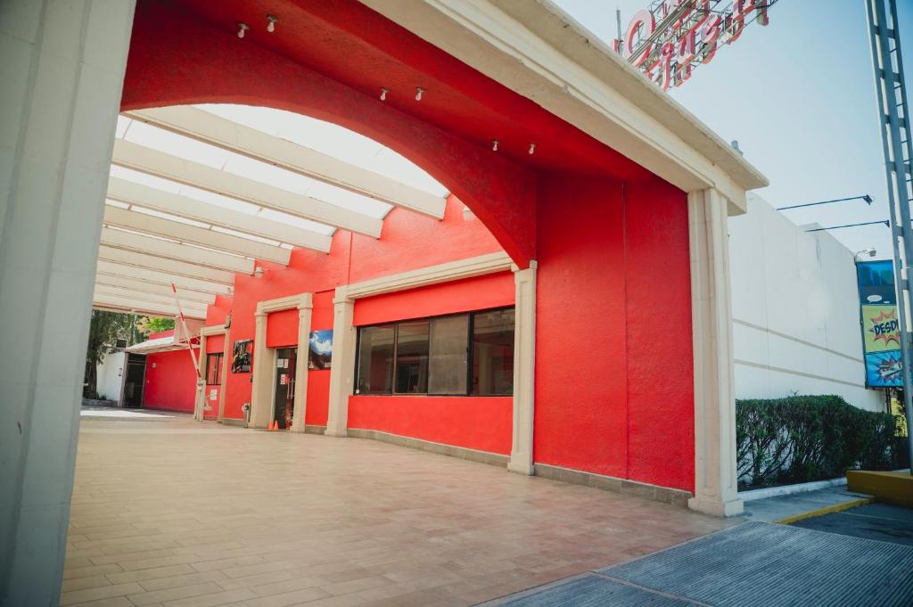 萨尔蒂约Hotel La Fuente, Saltillo的一座红色的建筑,在建筑的一侧有拱门