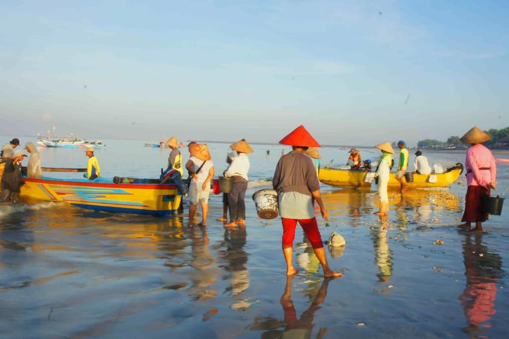 金巴兰芒果树别墅的一群人站在海滩上,坐船
