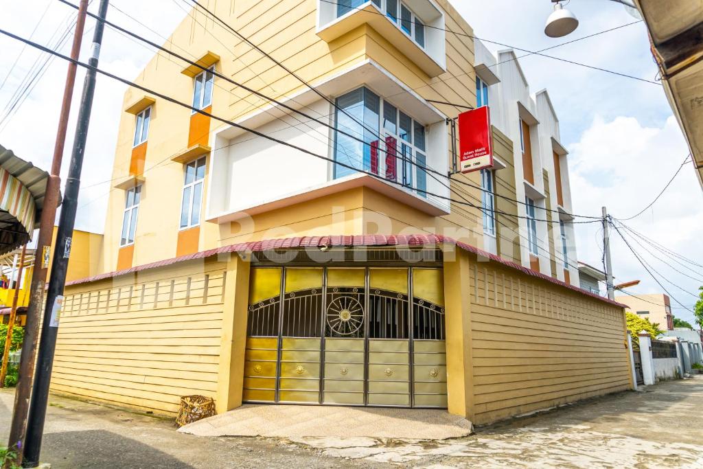 棉兰Adam Malik Guesthouse near Regale ICC Medan Mitra RedDoorz的一座黄色和白色的建筑,设有车库