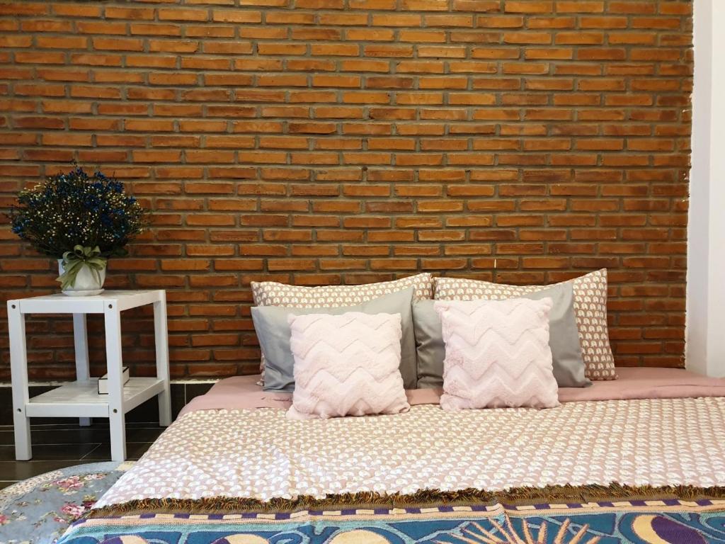 芹苴Nhu's House 2的砖墙前的一张带枕头的床