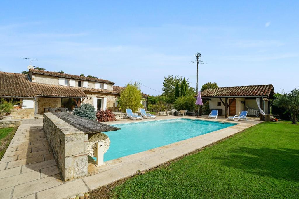 Saint-Sylvestre-sur-LotVilla de 4 chambres avec piscine privee jardin amenage et wifi a Saint Sylvestre sur Lot的一个带椅子的庭院和房子的游泳池