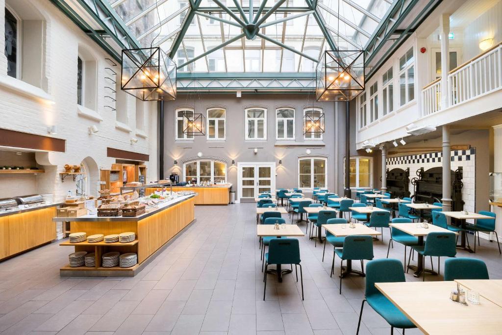 特隆赫姆贝斯特韦斯特普拉斯巴克列特酒店的餐厅设有桌椅和玻璃天花板
