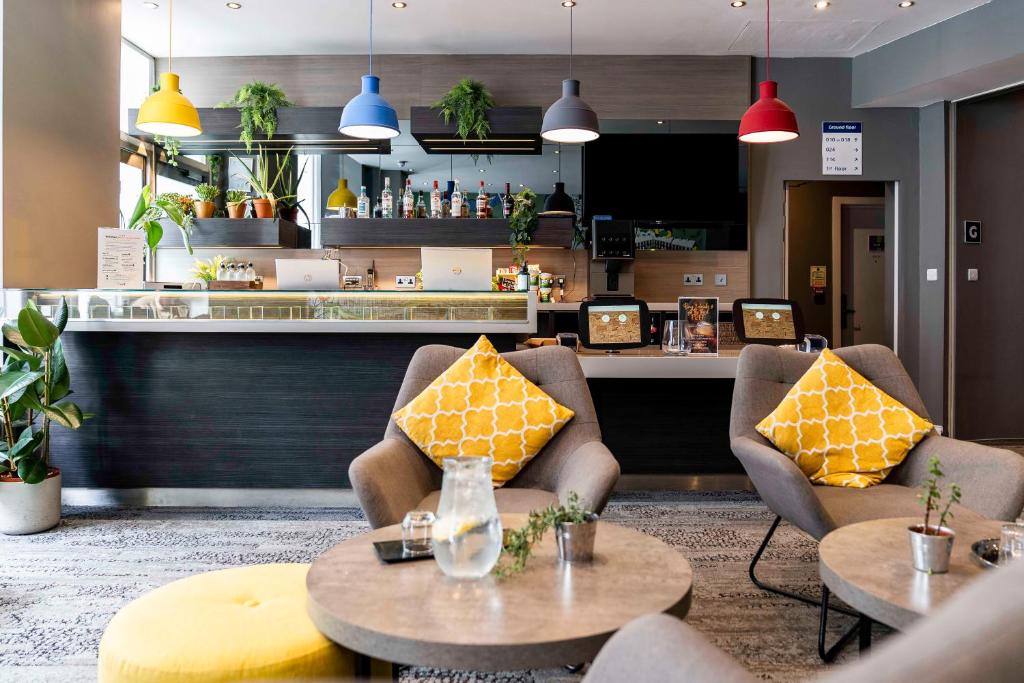 伦敦Heeton Concept Hotel - Kensington London的一间带两把椅子和桌子的餐厅以及柜台