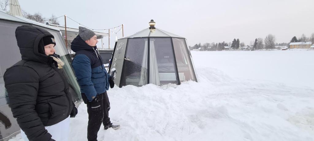 奥卢Koivuranta Igloos的两个人站在帐篷旁边的雪地里