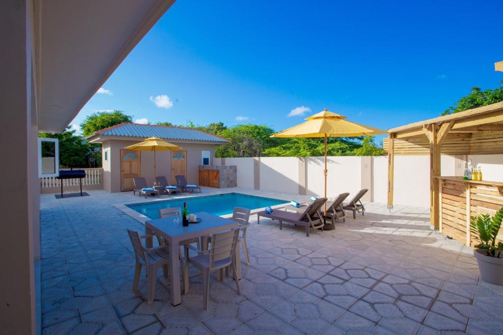 威廉斯塔德Lovely Caribbean family villa with private pool的一个带游泳池、桌椅和遮阳伞的庭院