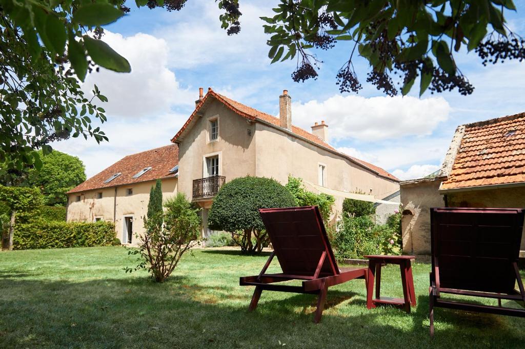 热夫雷尚贝尔坦Maison Laroze的两把椅子坐在房子前面的草上