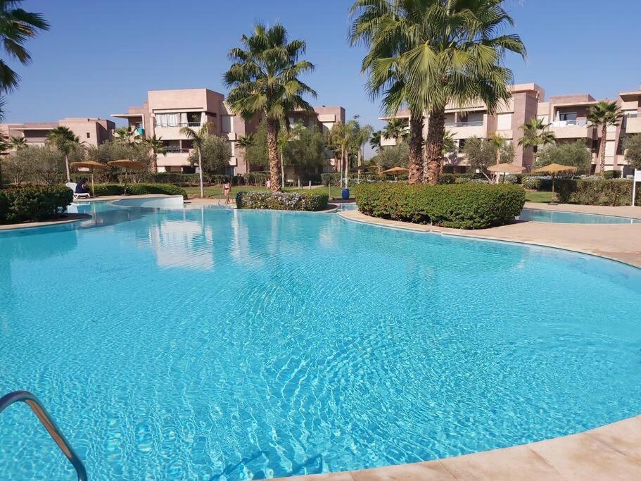 Appartement de luxe Prestigia Opale的一座种植了棕榈树和建筑的大型蓝色游泳池