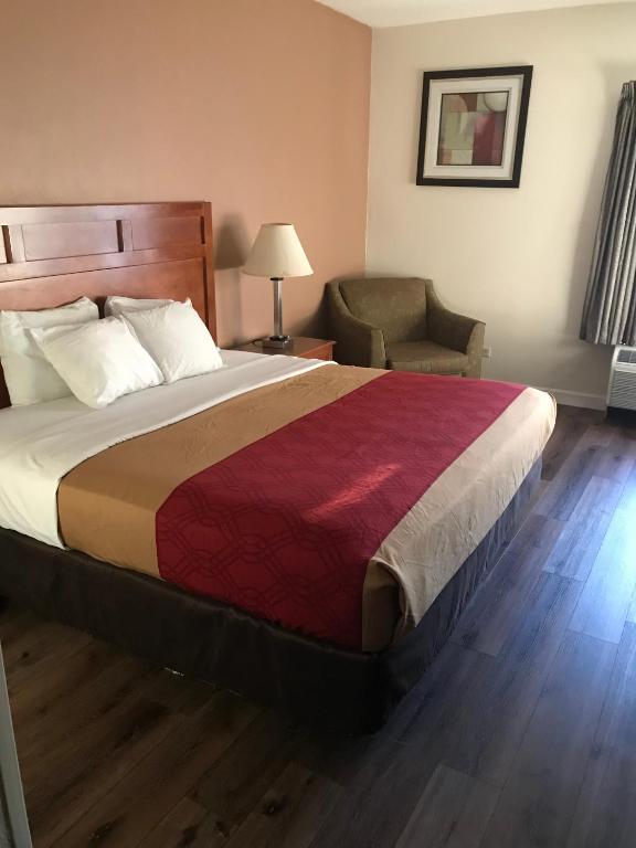 马克姆The Best Inn & Suites的酒店客房带一张大床和一把椅子