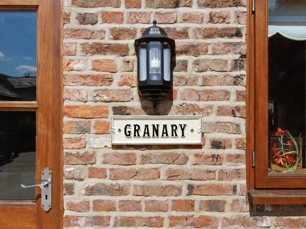 North Somercotes格兰纳里度假屋的砖墙上的路灯,上面有标志