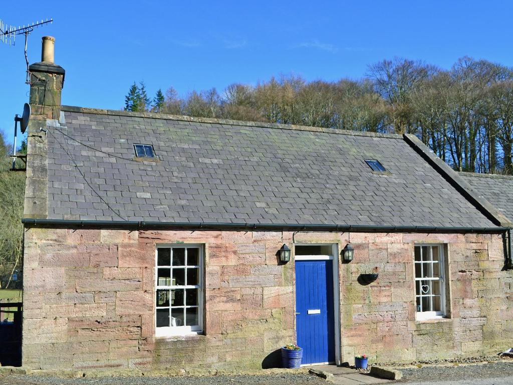 CarronbridgeWaulkmill Cottage的一座带蓝色门的旧砖砌建筑
