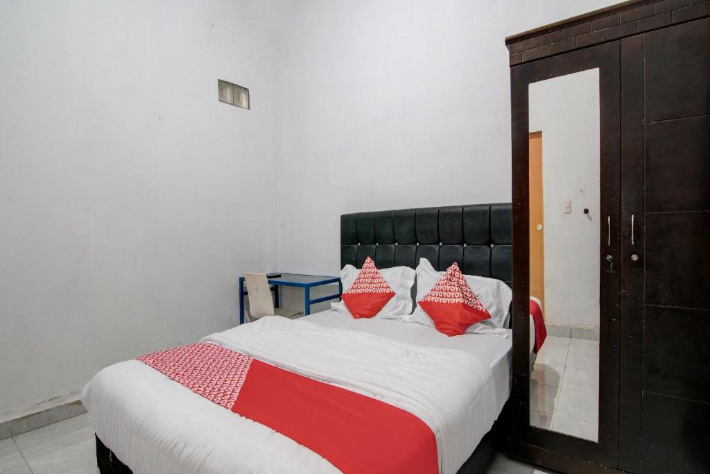 杜迈OYO 92111 Dinda Homestay Syariah的一间卧室配有红色和白色枕头的床