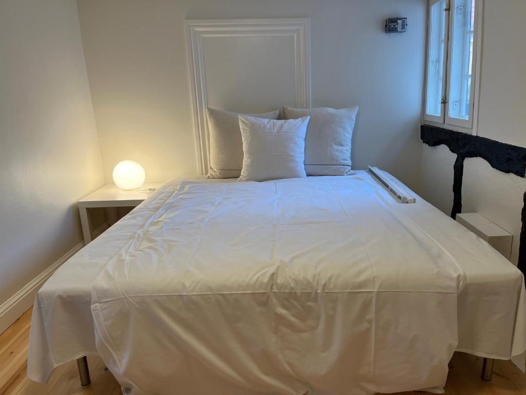 BallenKøbmandsgården的一张带白色床单和枕头的床