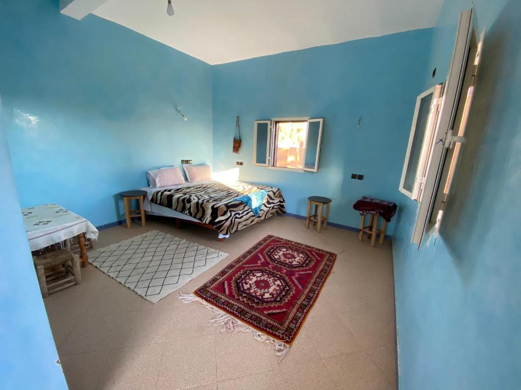 姆哈米德jardin du desert的一间卧室配有一张床、一张桌子和一张地毯。