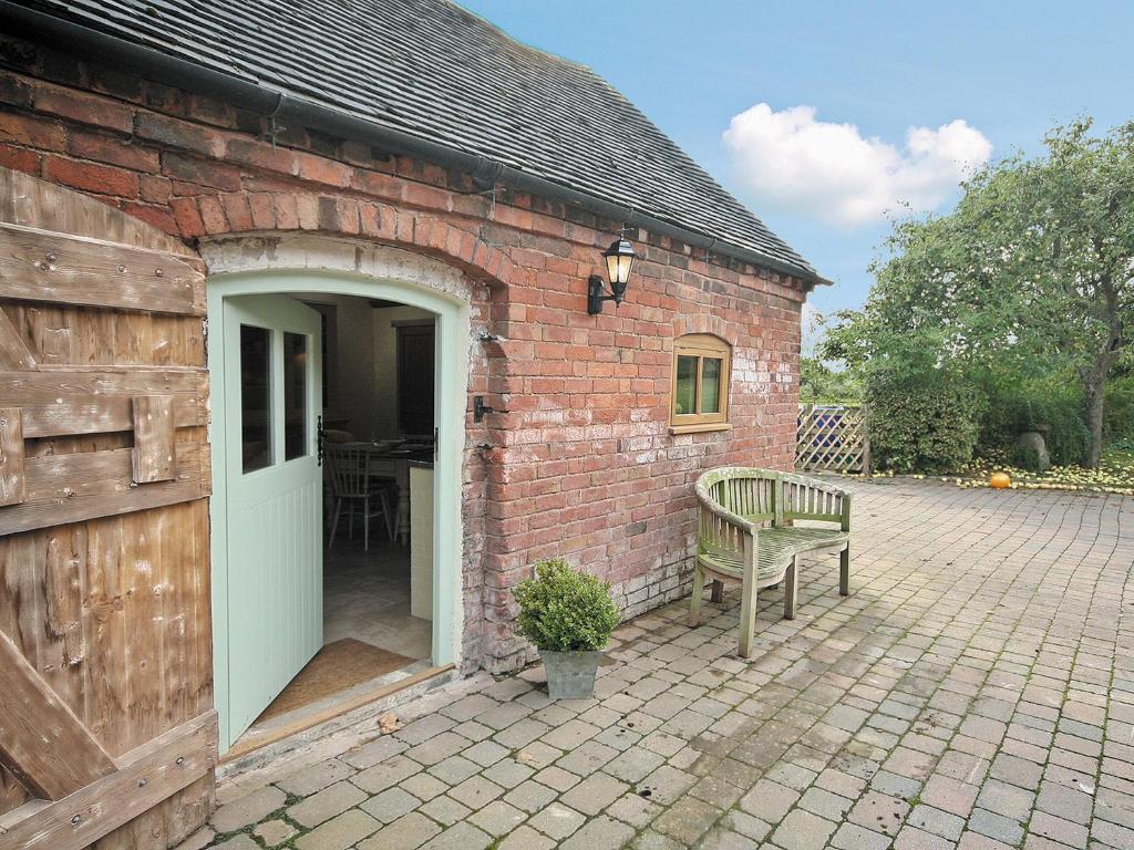 DunstallGrooms Cottage - E5398的砖砌建筑,设有开放式门和长凳