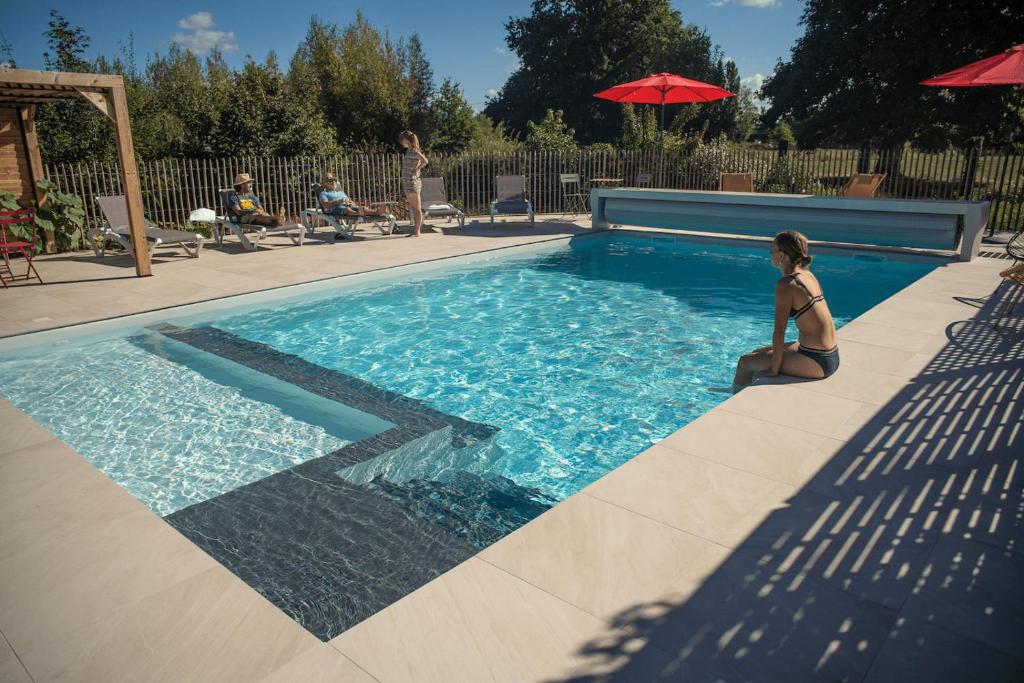 勒芒Le jardin des 4 saisons的坐在游泳池旁的比基尼的女人