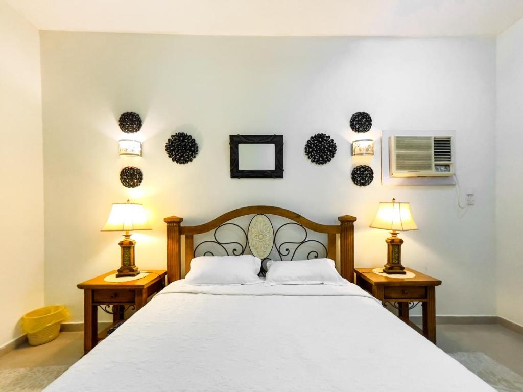Umm al ‘AmadSHAIKHA villa的卧室配有带两盏灯的白色床