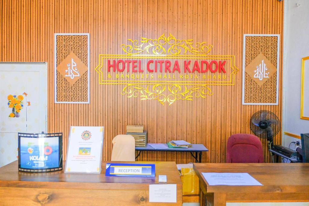 哥打巴鲁Citra Kadok Hotel & Banquet Hall的墙上有桌子和标志的房间