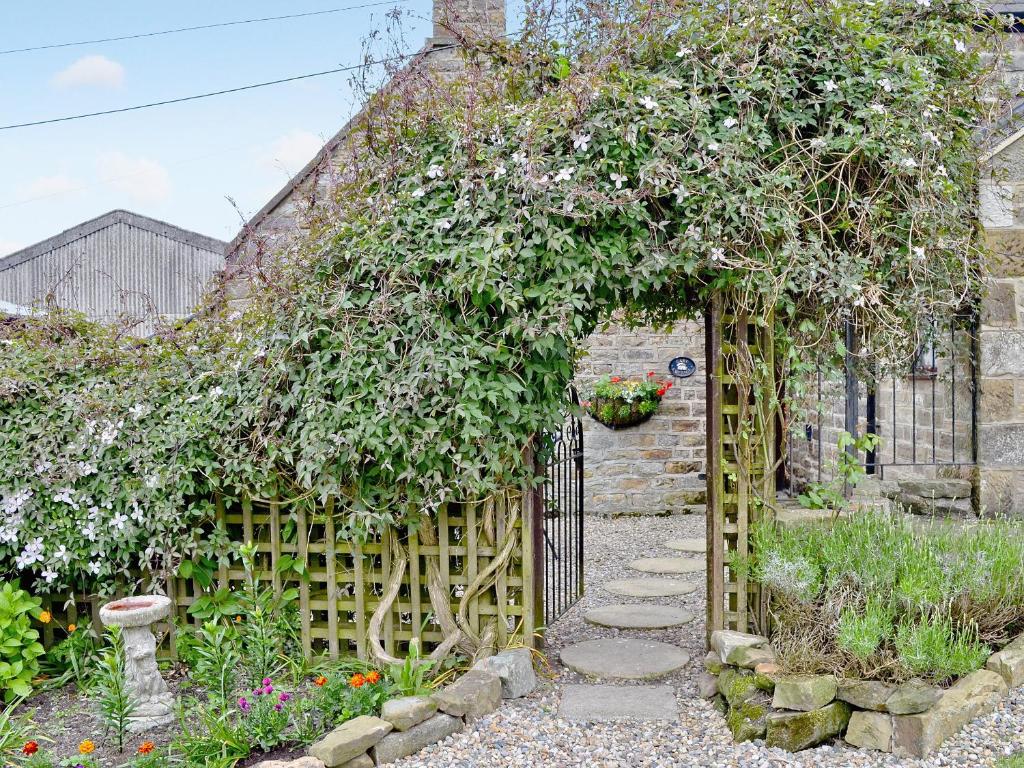 StaintondaleCart Cottage - 28343的花园设有木门和鲜花围栏