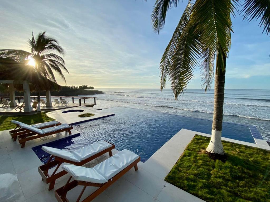 埃尔库科Vista Las Olas Resort的一个带椅子的游泳池,享有海景