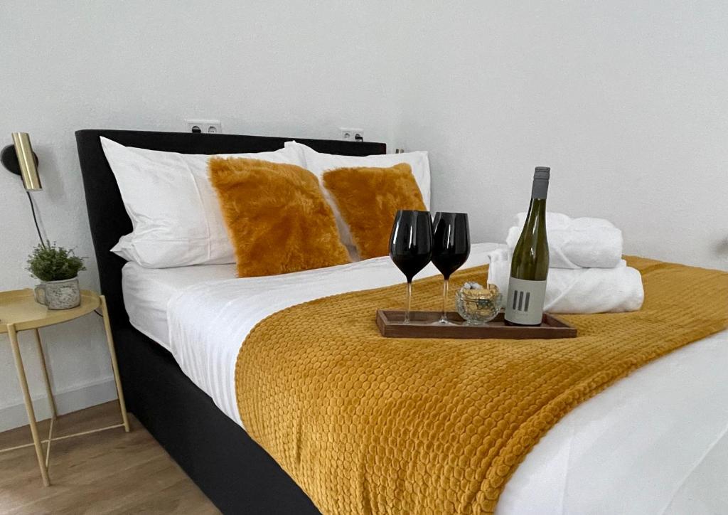 甘德尔克塞moor-home Studio Apartment的一张带托盘的床铺,托盘上放有两杯酒和一瓶葡萄酒