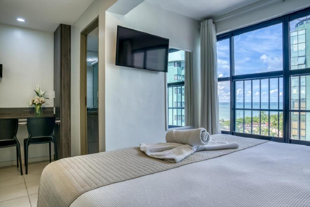 马塞约Vistamar Hotel的一间卧室配有一张带电视和书桌的床。