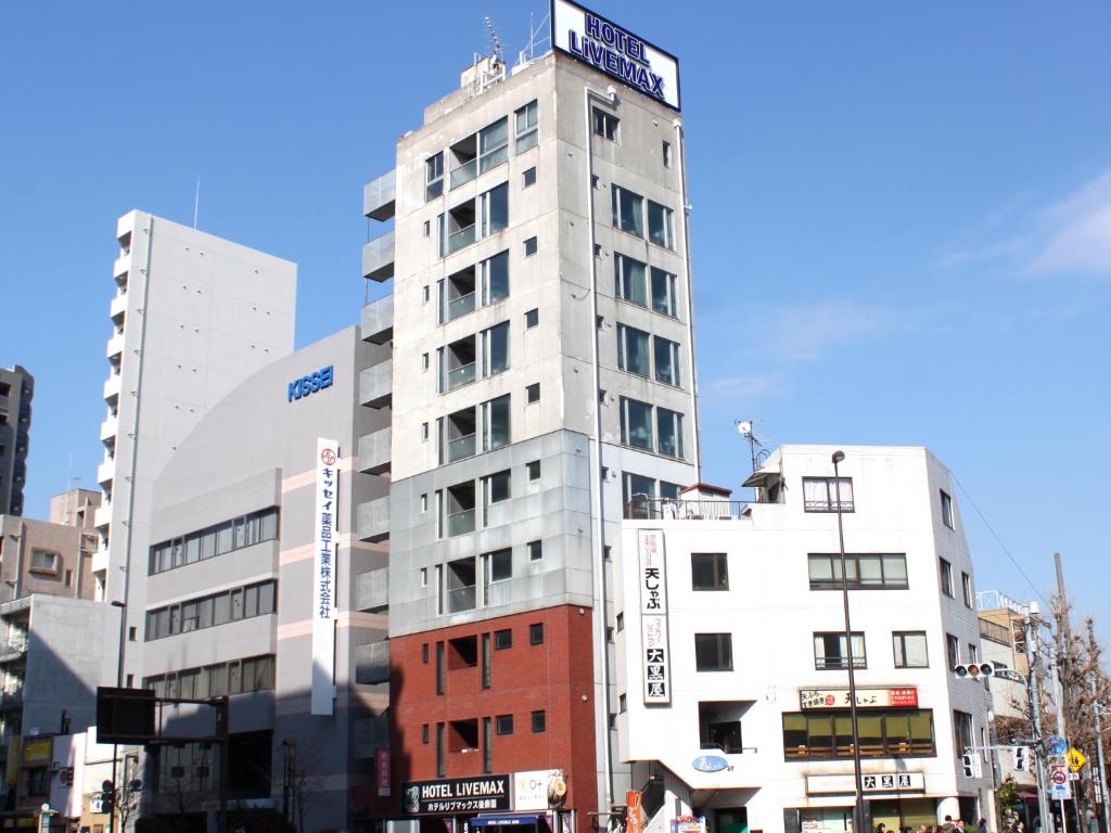 东京HOTEL LiVEMAX BUDGET Korakuen的一座高大的白色建筑,上面有标志