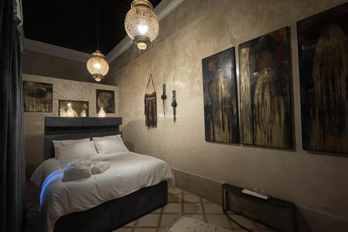 拉巴特Riad AL Bahi的一间卧室配有一张床,墙上挂着一些图片