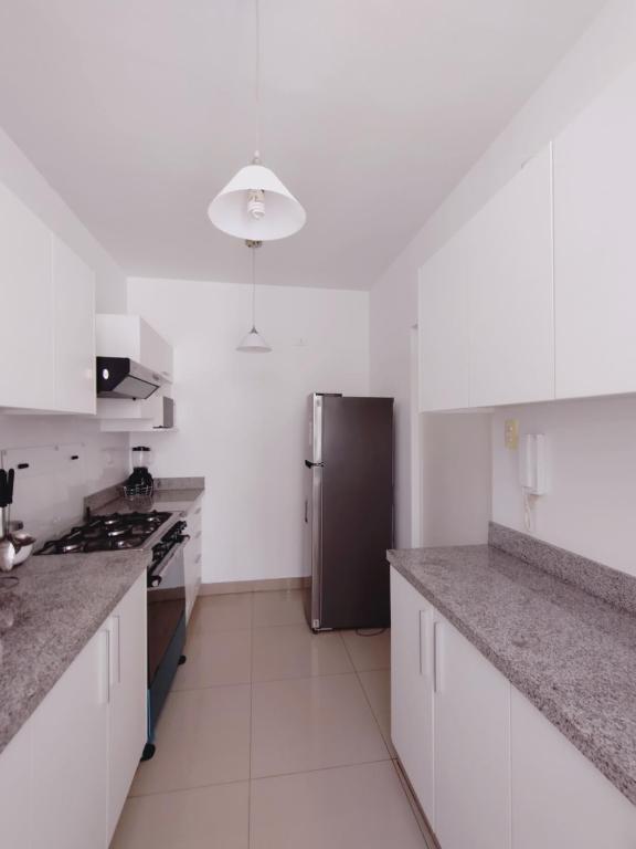 皮乌拉Acogedor Departamento 3 Hab Piura的厨房配有白色橱柜和不锈钢冰箱