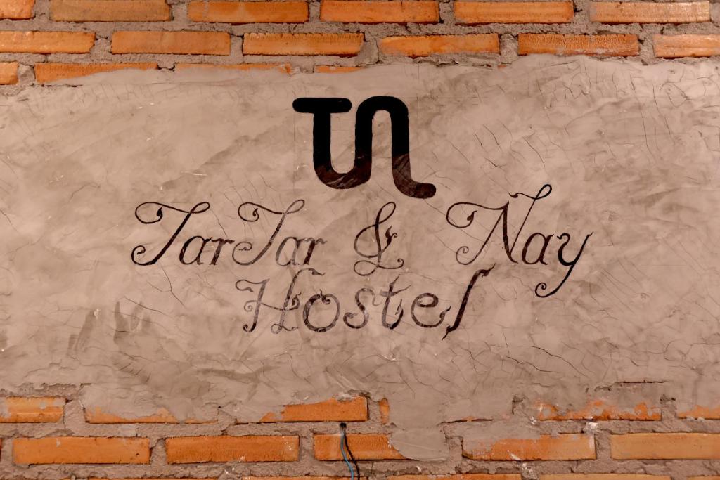 清迈TarTar & Nay Hostel的挂在砖墙上的标志,上面写着“纳帕家”的“U”字