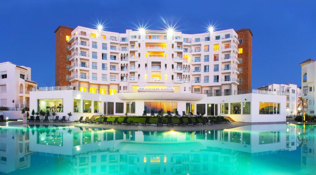 丹吉尔里亚德摩加多尔海景大酒店及水疗中心的一座白色的大建筑,前面设有一个游泳池