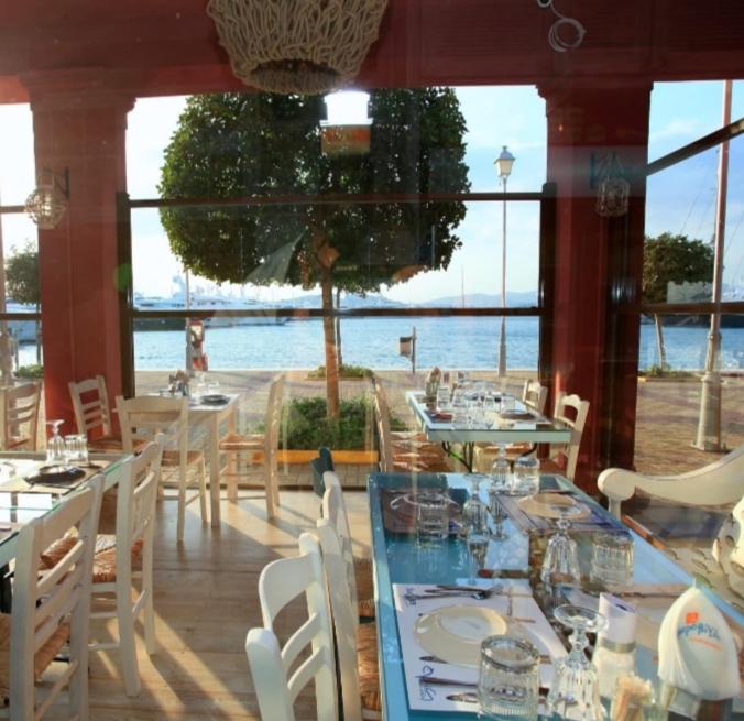 雅典Aphrodite Studio near Athens Floisvos Marina的一间带桌椅并享有水景的餐厅