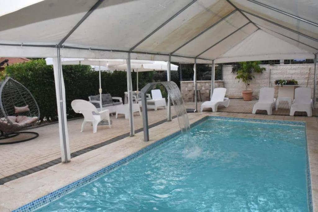 马格达拉Sounds Suite for families的一个带白色遮阳伞和椅子的游泳池以及一个游泳池