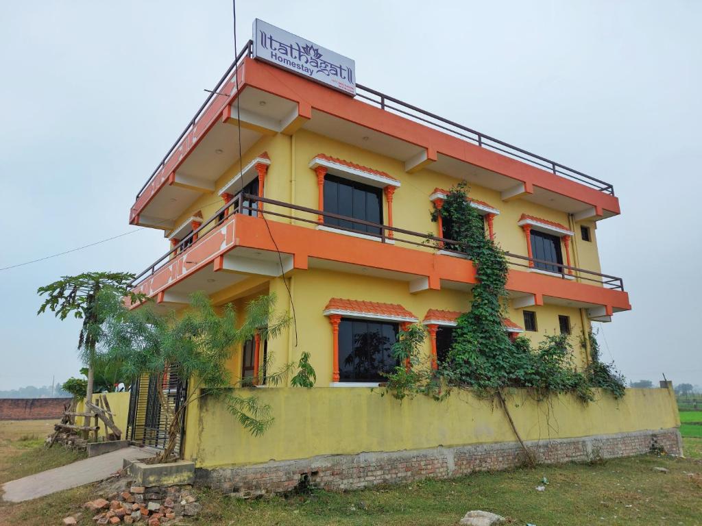 拉明德Tathāgata Homestay的黄色和橙色的房子,上面有标志