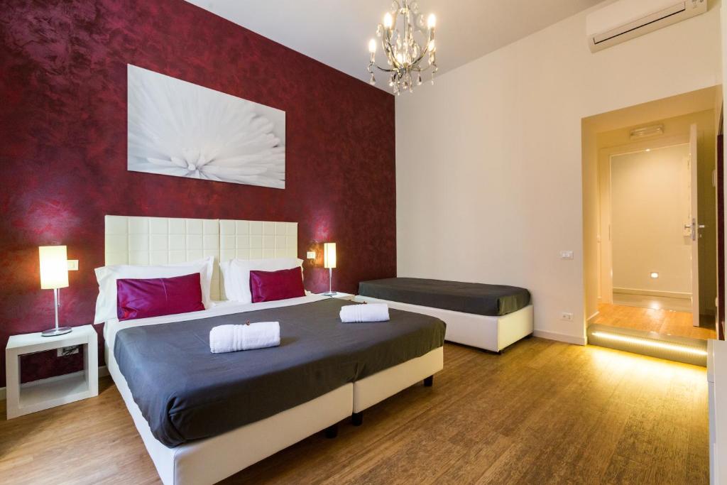 罗马亚历山大宾馆的一间卧室设有两张床和红色的墙壁