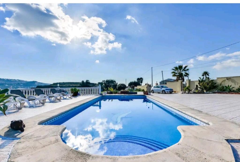 特乌拉达Casa de vacaciones con piscina comunitaria的一个带椅子的游泳池,蓝天