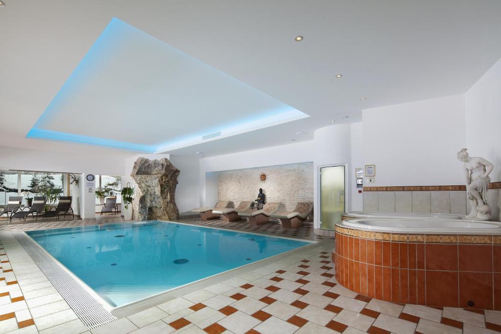 贝希特斯加登Alpenhotel Weiherbach Berchtesgaden Hallenbad und Sauna的一座大型游泳池,位于一座配有浴缸的建筑内