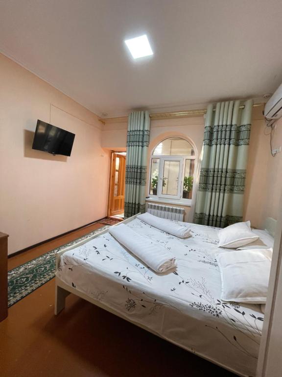 布哈拉Hotel Al Mansur的卧室配有一张大床,墙上配有电视